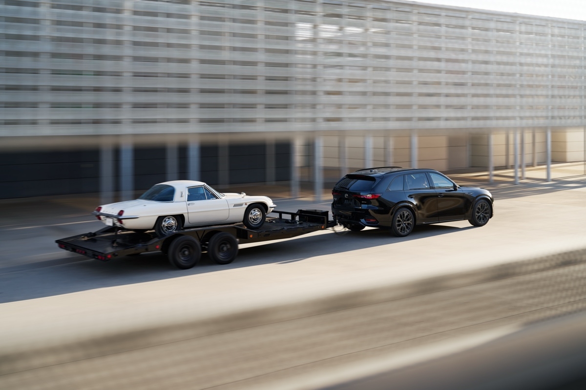 Mazda CX-70 2025 démontrant ses capacités de remorquage avec une remorque à voiture ancienne.